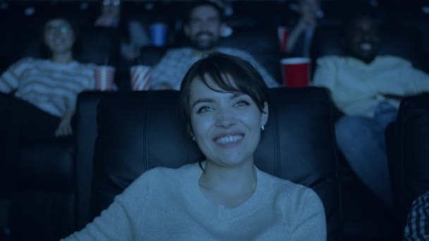 Медленное движение красивой женщины, смеющейся, смотрящей смешной фильм в темном кино — стоковое видео