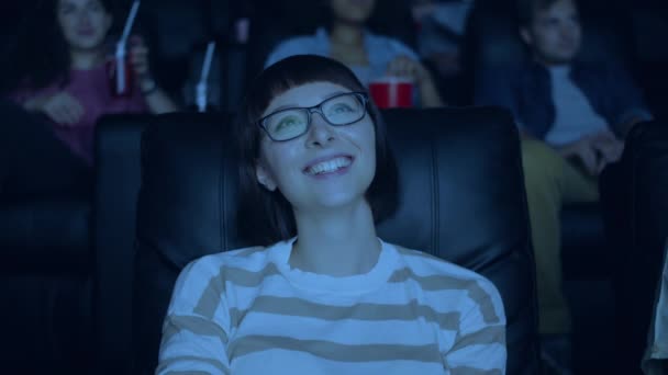 Attraktive Frau mit Brille lacht und amüsiert sich im Kino mit einer Gruppe von Menschen — Stockvideo