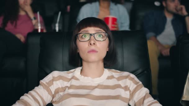 Fille effrayée dans des lunettes regarder un film effrayant au cinéma fermer les yeux avec la main — Video