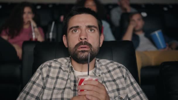 Horrified guy watching thriller in cinema holding drink screaming with fear — Stock Video