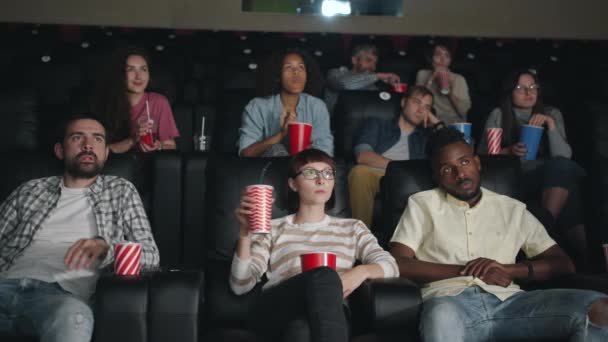 Movimento lento de homens e mulheres bocejando bebendo assistindo filme chato no cinema — Vídeo de Stock