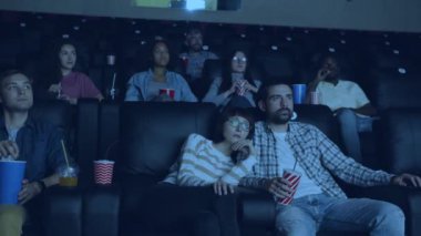 Modern sinemada içecek ve atıştırmalıklarla film izleyen kaygısız yetişkinler