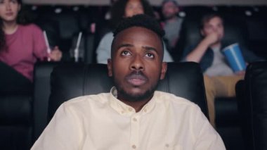 Korkmuş Afro-Amerikan adam sinemada korku filmi izlerken yavaş hareket