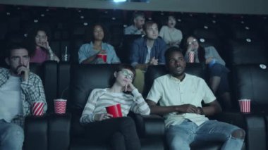 Mutsuz izleyiciler birlikte sıkıcı film izlerken sinema salonunda esneme