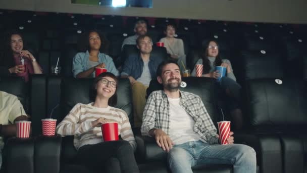 Jóvenes alegres viendo comedia en el cine riendo mirando la pantalla — Vídeo de stock