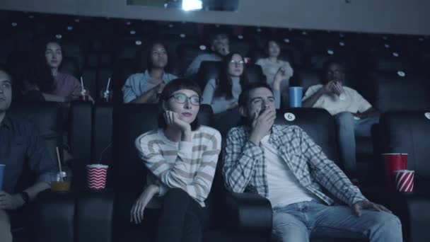 男人打哈欠伸展手臂，然后拥抱女人在电影院在现代约会 — 图库视频影像