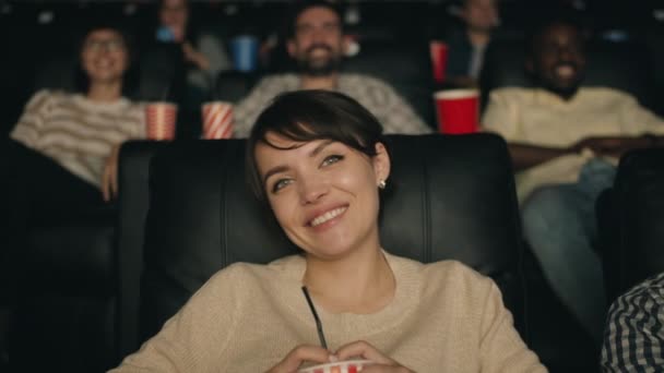 Ralentir le mouvement de la femme joyeuse riant en regardant un film au cinéma tenant boisson — Video