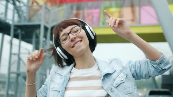 Retrato de mujer alegre escuchando música en auriculares bailando al aire libre — Vídeos de Stock