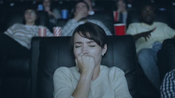 Attraktives Mädchen, das bei Horrorfilm im dunklen modernen Kino Angst bekommt — Stockvideo