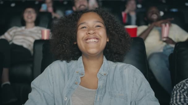 Portræt af glad afrikansk amerikansk teenager griner ser film i biograf – Stock-video