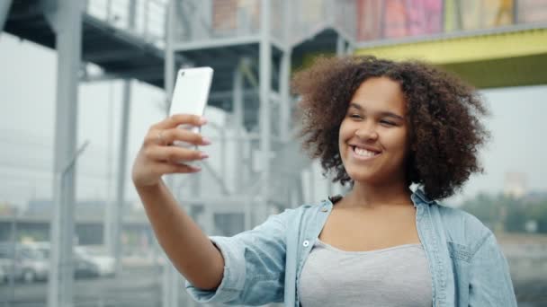 Zeitlupe: hübsche Afroamerikanerin macht Selfie mit Smartphone im Freien — Stockvideo
