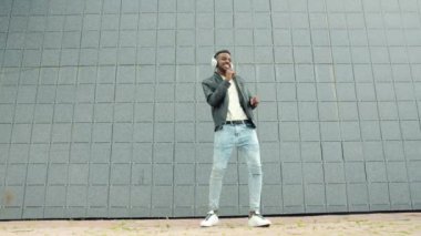 Afro-Amerikan öğrenci şehir caddesinde kulaklık dans eğleniyor