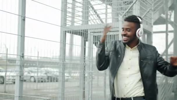 Afro-américain gars chantant la danse profiter de la musique dans les écouteurs en plein air — Video