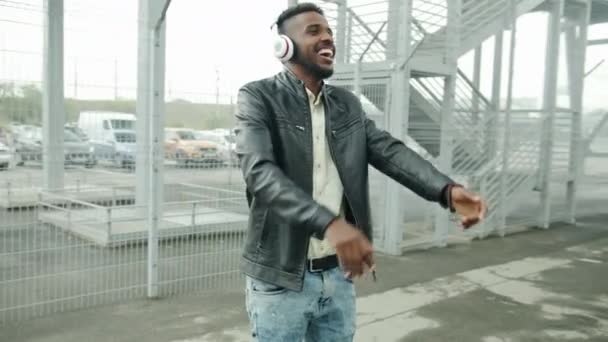 Gelukkig African American student in koptelefoon dansen buitenshuis plezier — Stockvideo