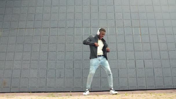 Hipster afroamericano en auriculares bailando al aire libre divirtiéndose — Vídeo de stock