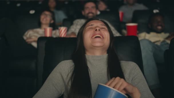 Веселая девушка смеется, смотря фильм в кино, поедая попкорн, веселясь. — стоковое видео