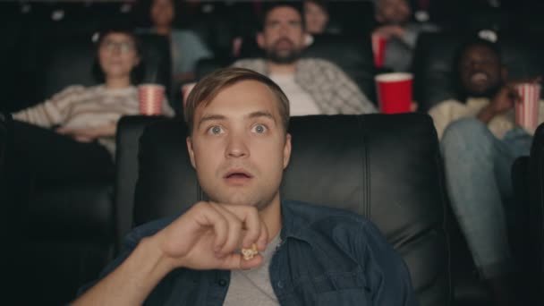 Shocked student watching film in cinema with open mouth eating popcorn smiling — Stock Video