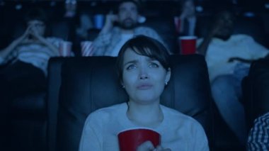 Güzel kız üzgün film izlerken ve sinemada patlamış mısır yeme yavaş hareket