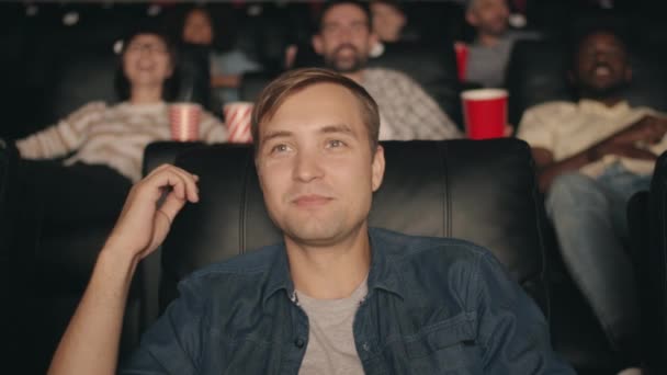 Movimento lento de homem alegre assistindo filme no cinema com pipoca e suco de frutas — Vídeo de Stock