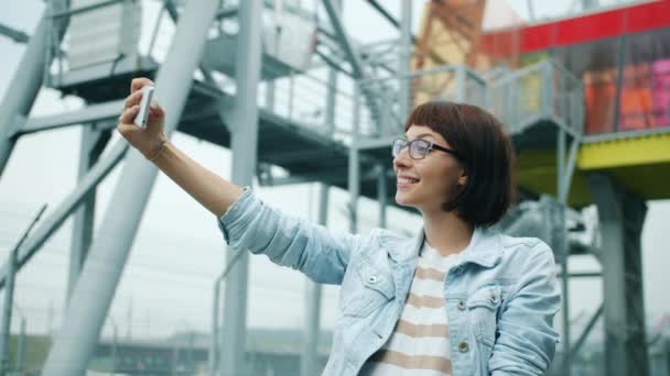 Mutlu genç kadının dışarıda akıllı telefon kamerasıyla selfie çektiği portresi — Stok video