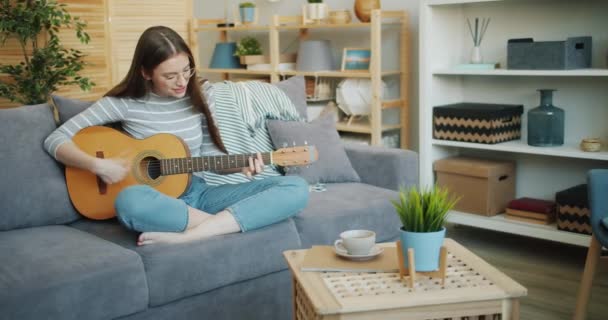 Slow Motion van mooi meisje speelt gitaar thuis met plezier alleen — Stockvideo