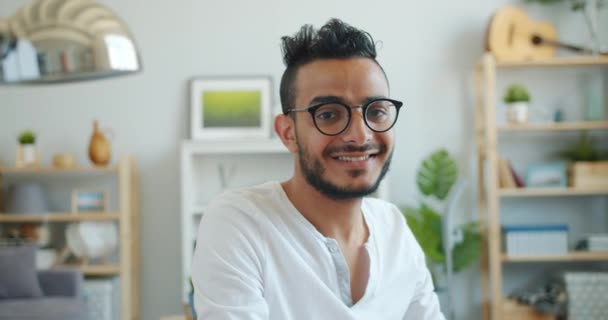 Retrato de chico árabe guapo en gafas mirando a la cámara interior en casa — Vídeo de stock
