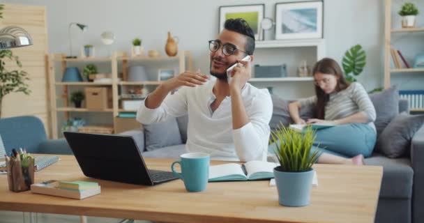 Lassított Arab beszél a mobiltelefonon, miközben nő olvasatban a háttérben — Stock videók