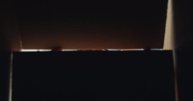 Neşeli Afro-Amerikan adam açılış kutusu nun yavaş hareket gülümseyerek içine bakarak