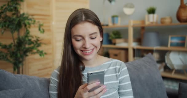 Portrait de belle fille à l'aide d'un smartphone, puis en regardant la caméra sourire — Video