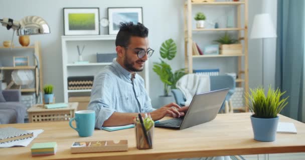 Slow Motion van mannelijke freelancer met laptop aan tafel in appartement typen — Stockvideo