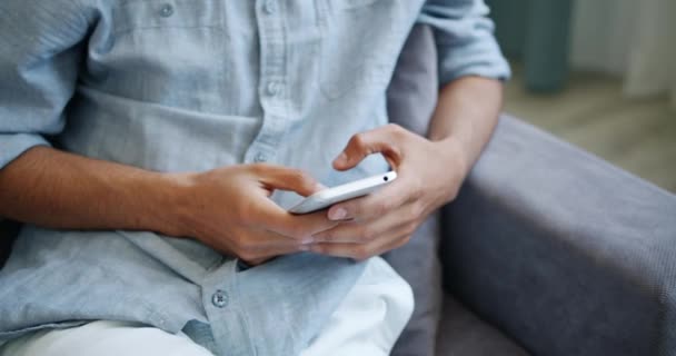 Крупним планом чоловічі руки за допомогою смартфона торкаючись екрану в приміщенні вдома — стокове відео