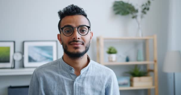 Portret van gelukkig goed uitziende Arabische kerel glimlachend en kijken naar de camera thuis — Stockvideo