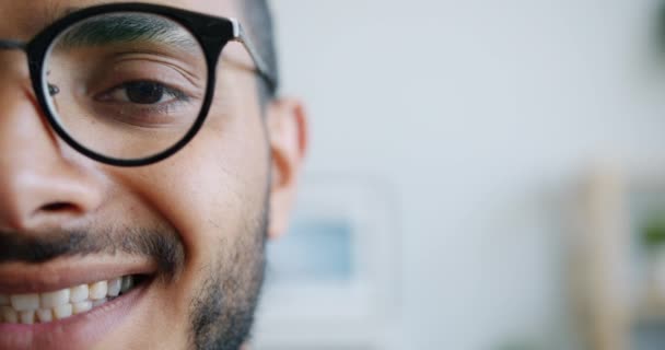 Retrato de cerca de la mitad de la cara masculina mirando a la cámara sonriendo en el interior — Vídeos de Stock