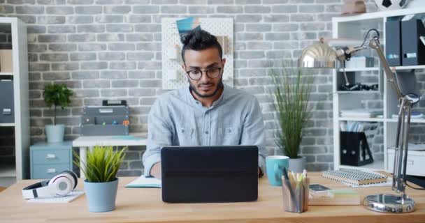 Mann aus dem Nahen Osten arbeitet mit Laptop im Loft-Büro und tippt am Schreibtisch — Stockvideo