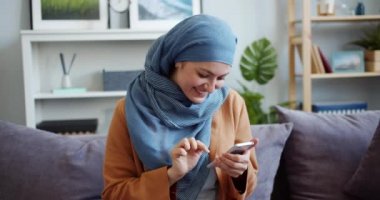 Evde akıllı telefon dokunmatik ekran kullanarak hijab Gülümseyen karışık yarış kız