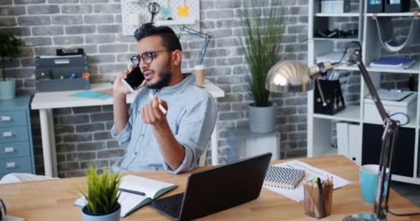 Zły pracownik biurowy Młody Arab rozmawia na telefon komórkowy na biurku uczucie podrażniona — Wideo stockowe