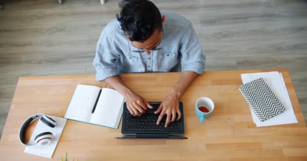 Movimento lento do trabalhador de escritório árabe digitando usando laptop, em seguida, esticando os braços — Vídeo de Stock