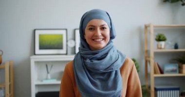 Dairede kameraya bakarak gülümseyen türbanlı mutlu Müslüman bayan Portresi