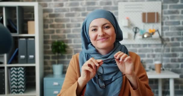 Портрет мусульманской предпринимательницы в хиджабе, держащей бокалы, сидящие в кабинете — стоковое видео