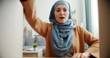 Şaşırmış Orta Doğulu kadın hijab açılış karton kutu hediye alarak gülümseyerek