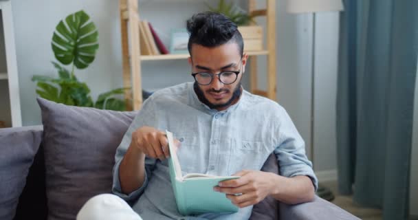 Atractivo hombre afroamericano leyendo interesante libro en casa solo — Vídeos de Stock