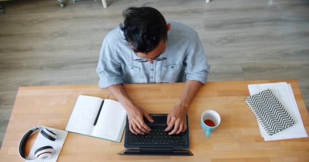 Hög vinkel bild av afrikansk amerikansk man med hjälp av laptop skriva i kontorsrum — Stockvideo