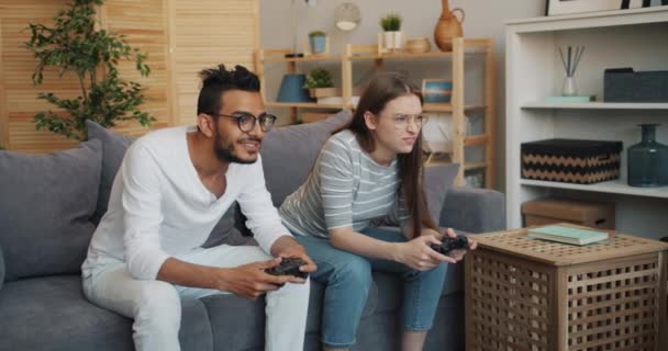 Мужчина и женщина счастливая пара наслаждаются видеоигрой в квартире весело — стоковое видео