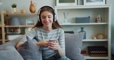 Güzel genç kadın akıllı telefon kullanarak kulaklık ile müzik dinliyor
