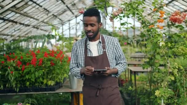 Slow motion afroamerikansk kille som använder Tablet i växthus ser runt — Stockvideo