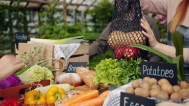 Çiftlik pazarında alıcıya organik sebze torbası veren satış elemanının yakın çekim