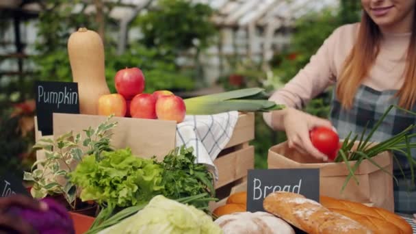 Продажі дівчина упаковка свіжих овочів в паперовий мішок на ринку ферм — стокове відео