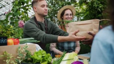 Erkek ve kadın çiftlik pazarında para alarak müşterilerine organik gıda veren