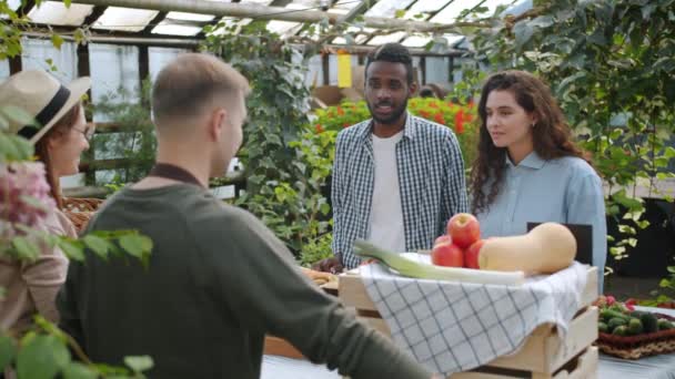 Movimiento lento de los jóvenes que eligen verduras orgánicas en el mercado agrícola en interiores — Vídeo de stock