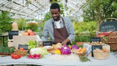 Afrikalı Amerikalı adam çiftçi çiftlik pazarında masaya organik gıda koyarak